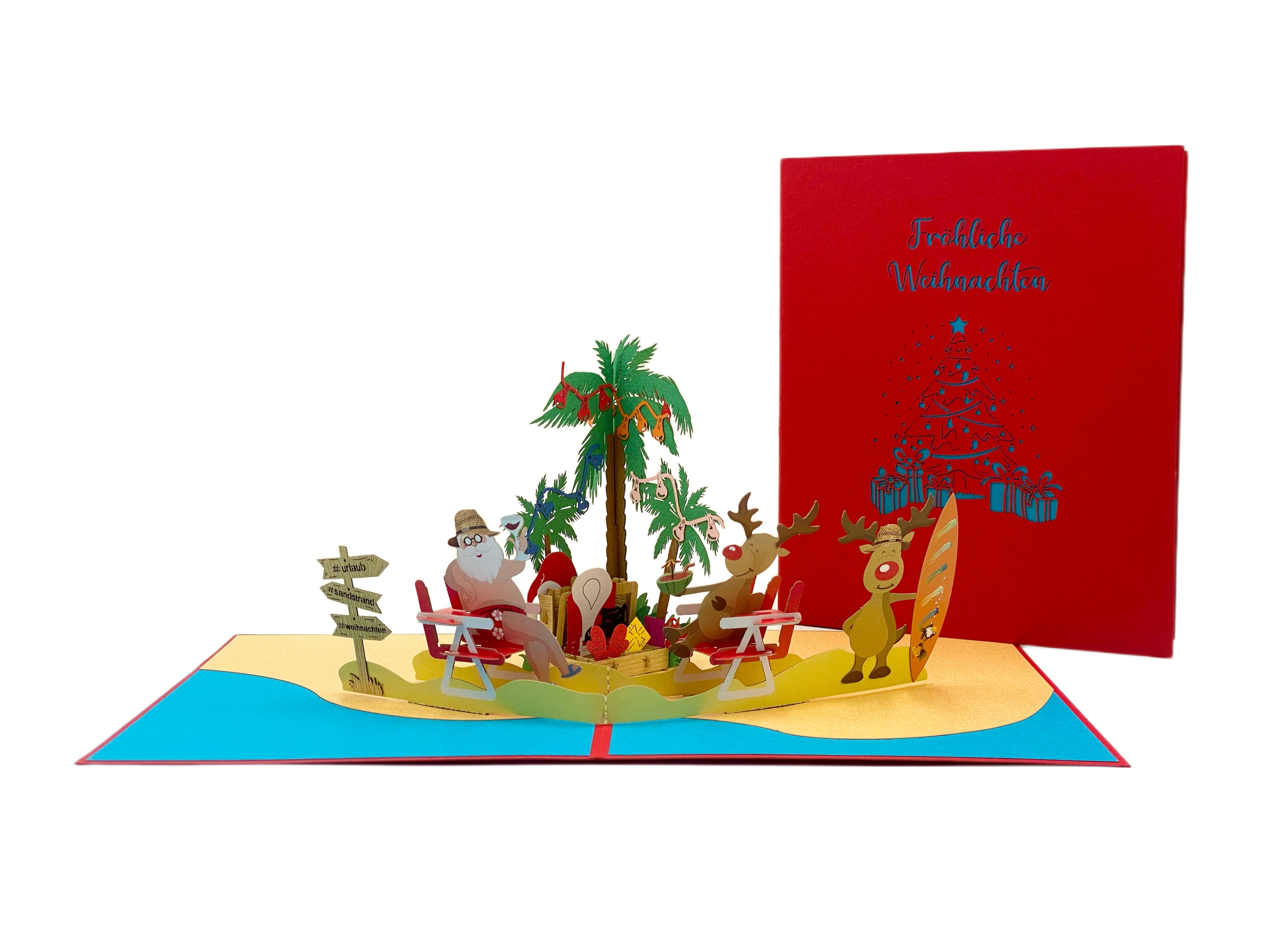 Aufgeklappte Pop-up-Karte mit Weihnachtsmann am Strand, daneben die rote Kartenvorderseite mit dem Schriftzug Fröhliche Weihnachten und einem blauen Weihnachtsbaum aus Geschenken.