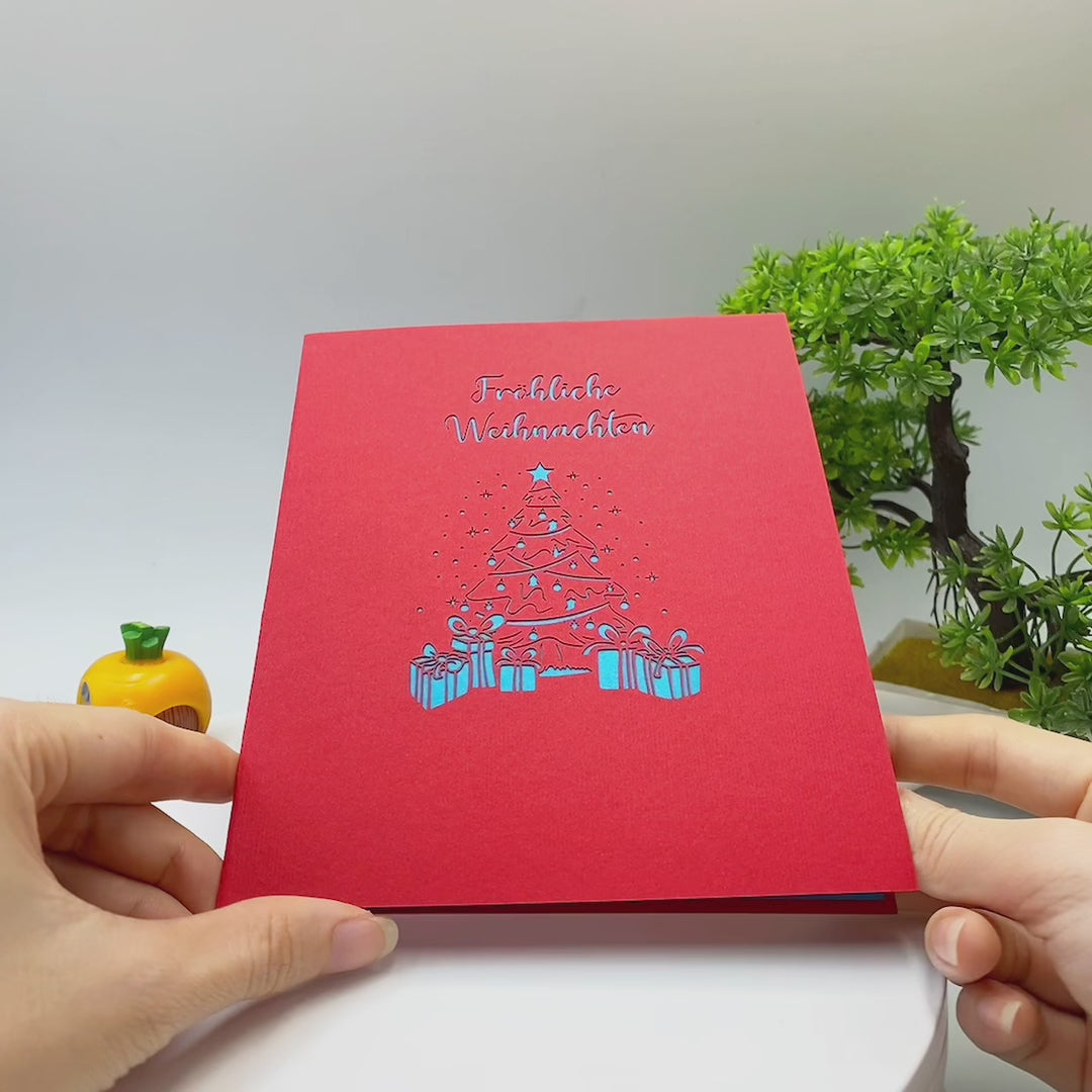 Video: Die rote Kartenvorderseite mit dem Schriftzug Fröhliche Weihnachten und blauem Weihnachtsbaum wird in den Händen aufgeklappt.