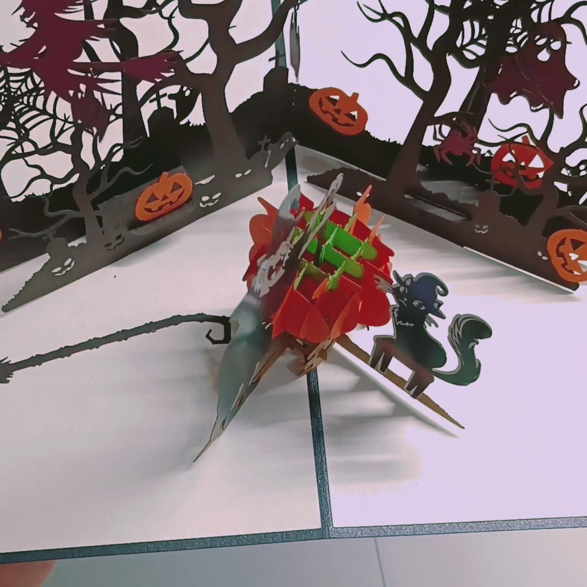Video: Aufgeklappte Halloween Pop-up-Karte mit Kürbissen, schwarzer Katze und kahlen Bäumen.