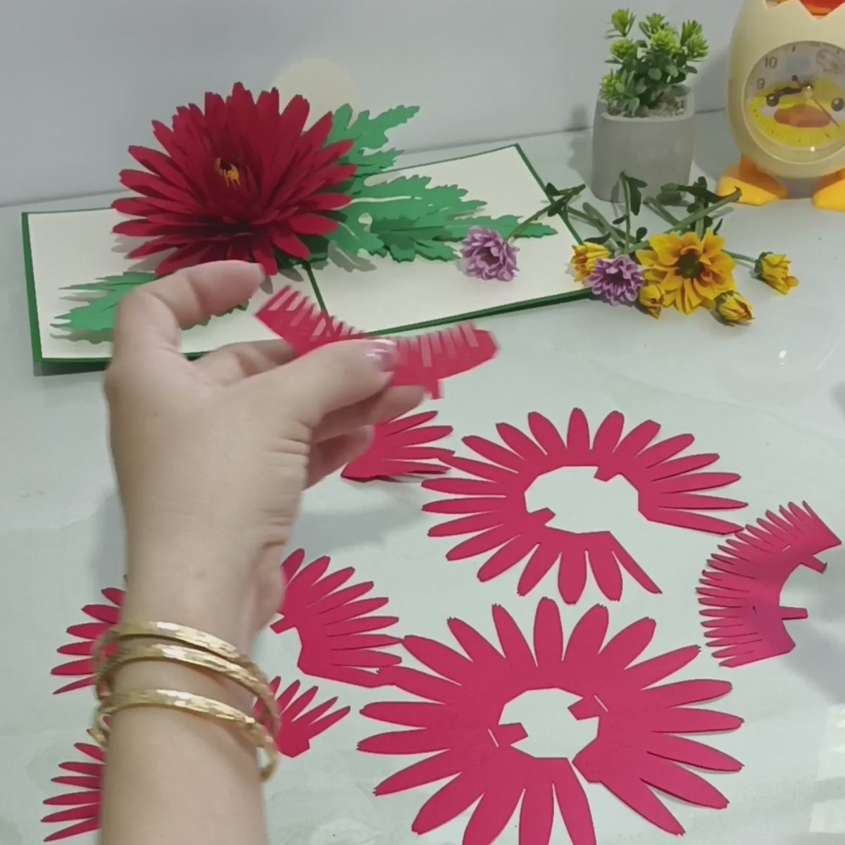 Video: Herstellung der Chrysanthemen Pop-up-Karte – pinke Blütenteile aus Papier werden von Hand zusammengesetzt.