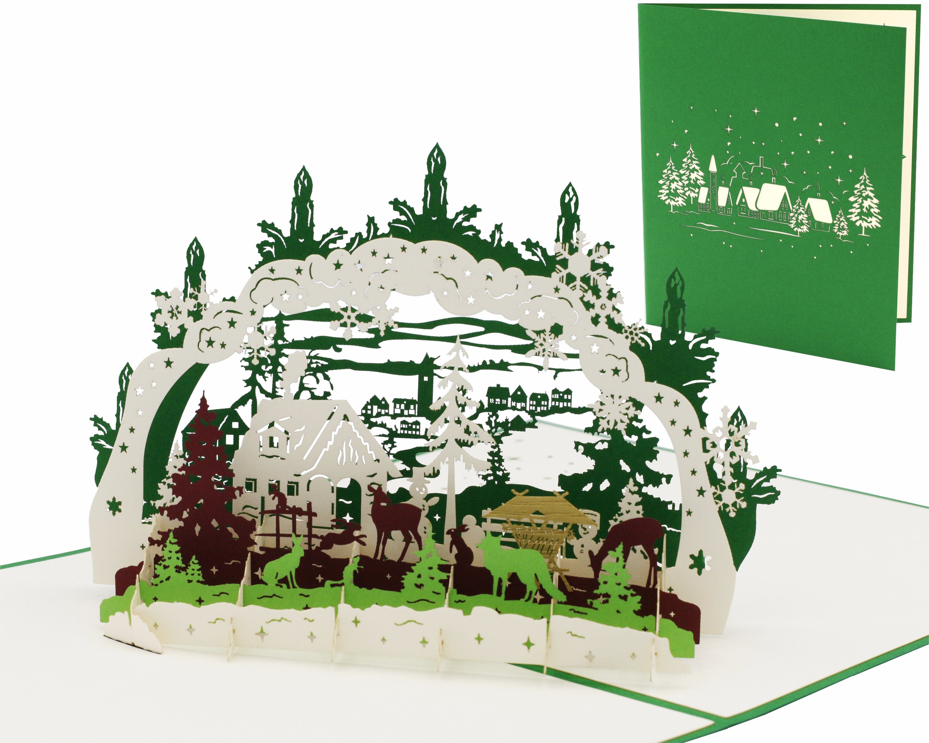 Aufgeklappte Pop-up-Karte mit einem Schwibbogen mit Winterlandschaft, daneben die grüne Kartenvorderseite mit Schwibbogen-Scherenschnitt.