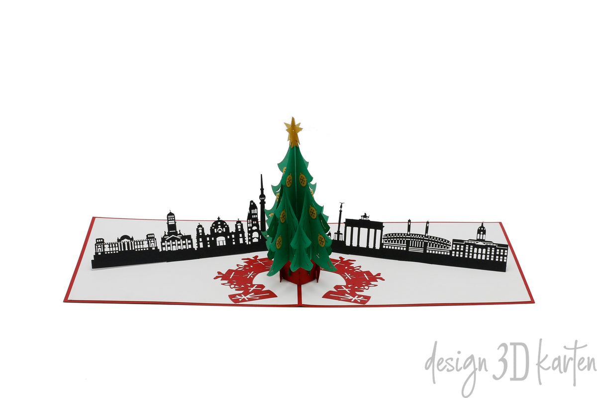 Aufgeklappte Pop-up-Karte mit grünem Weihnachtsbaum vor der Berliner Skyline mit Brandenburger Tor und Fernsehturm.