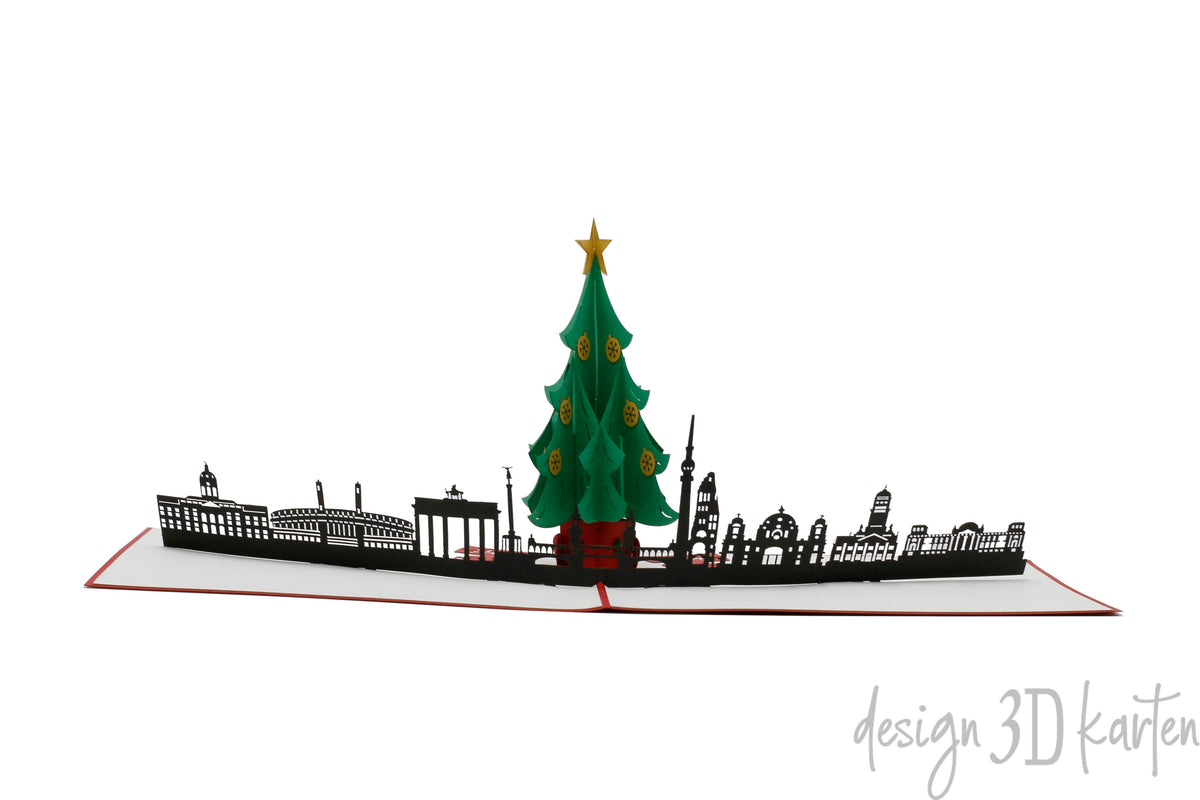 Aufgeklappte Pop-up-Karte mit Weihnachtsbaum vor der Skyline von Berlin, seitlich fotografiert.