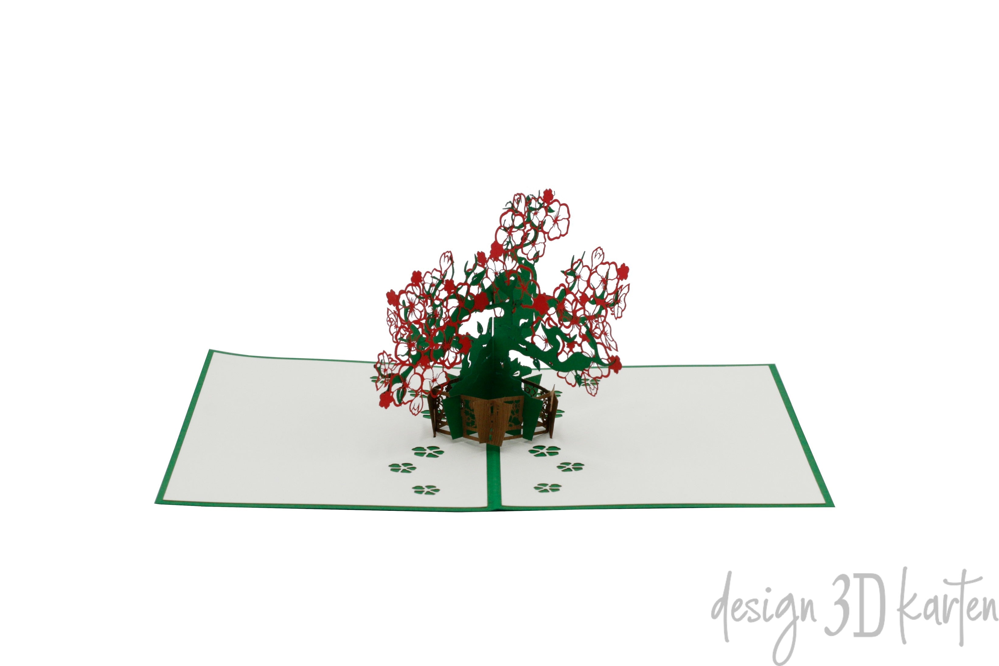 Aufgeklappte Pop-up-Karte mit filigranem Blumenbonsai aus Papier, schräg von der Seite fotografiert.