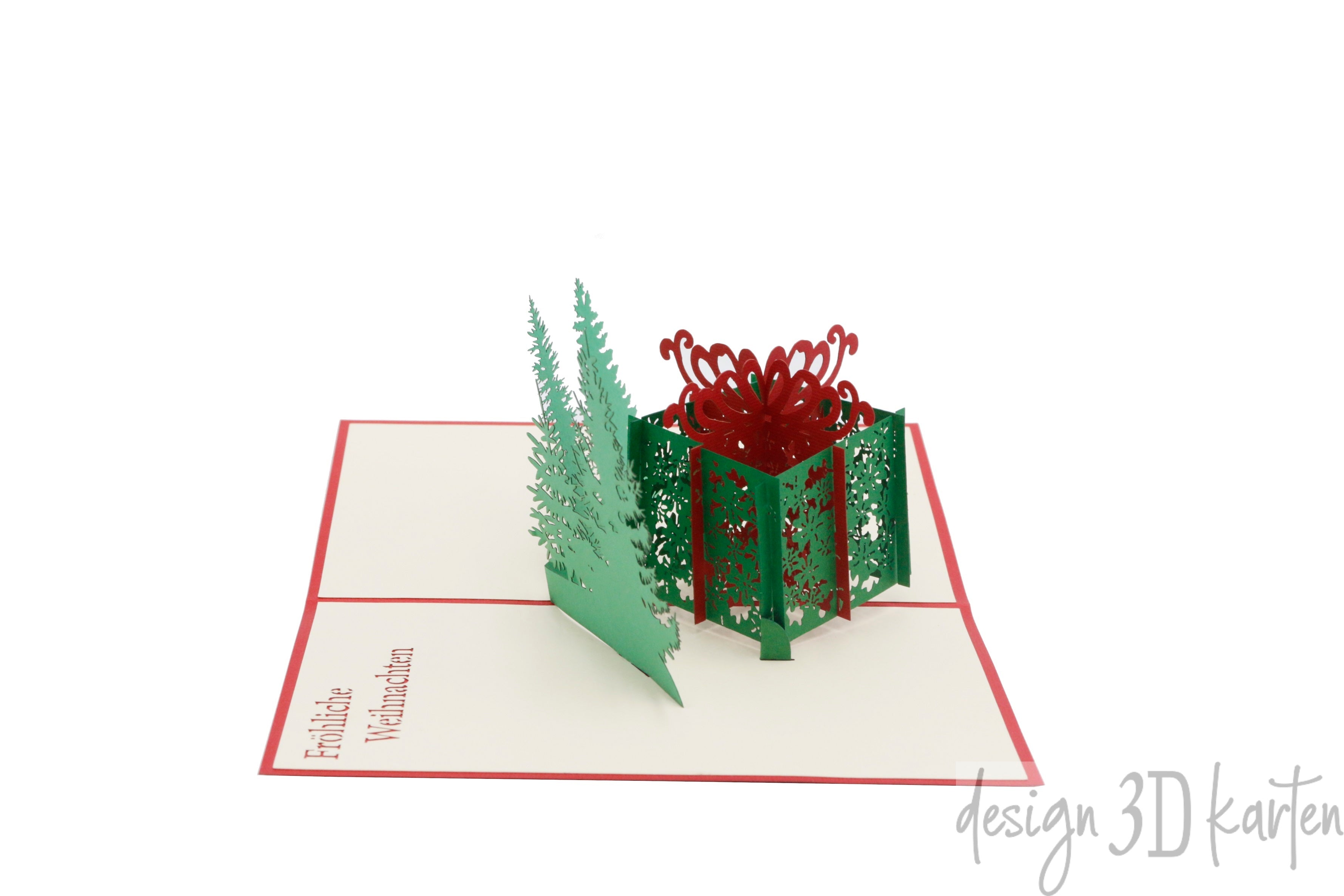Aufgeklappte Pop-up-Karte mit Geschenkbox und Tannen, schräg von der Seite fotografiert.