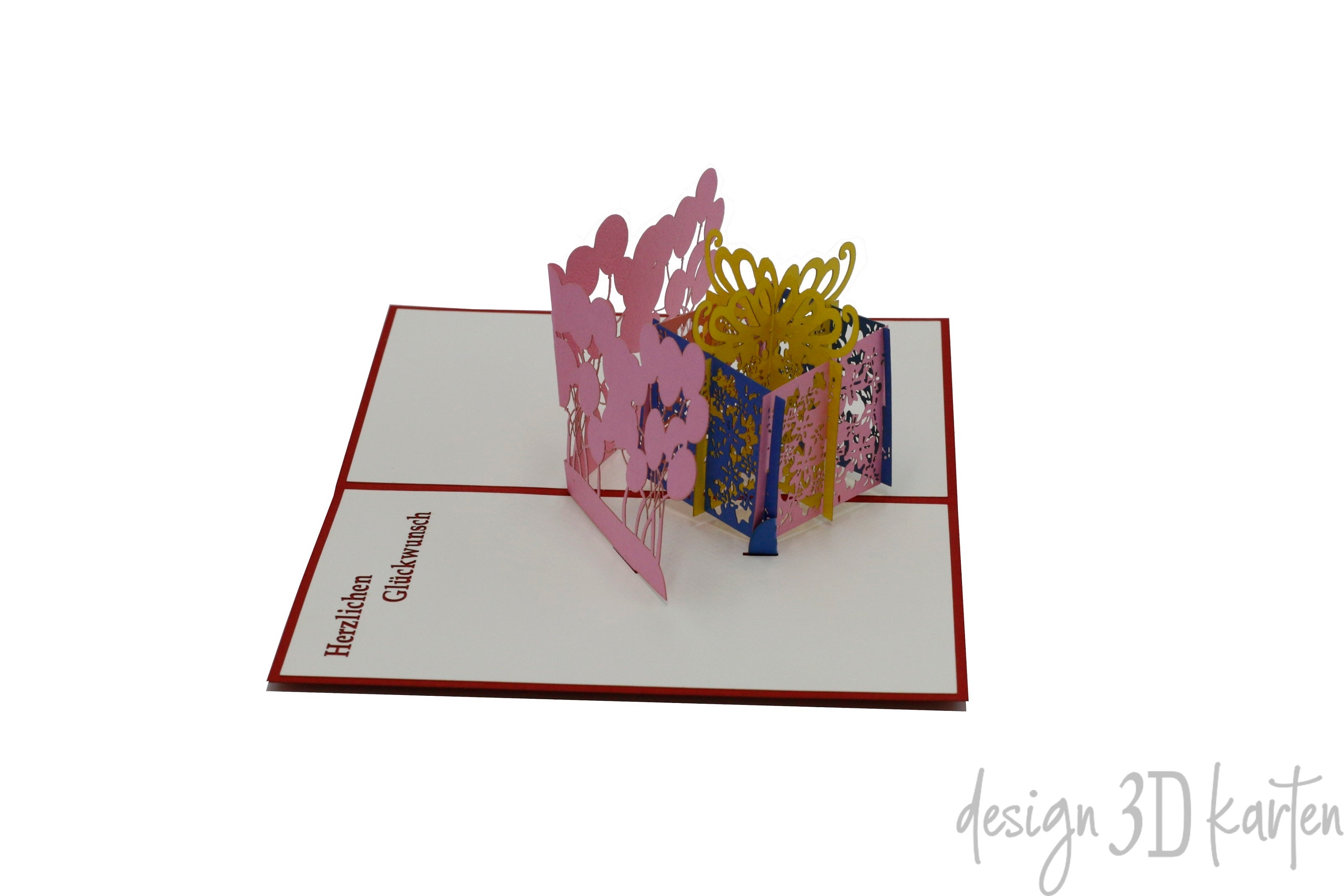 Aufgeklappte Pop-up-Karte mit rosa-gelber Geschenkbox und Luftballons, schräg von der Seite fotografiert.