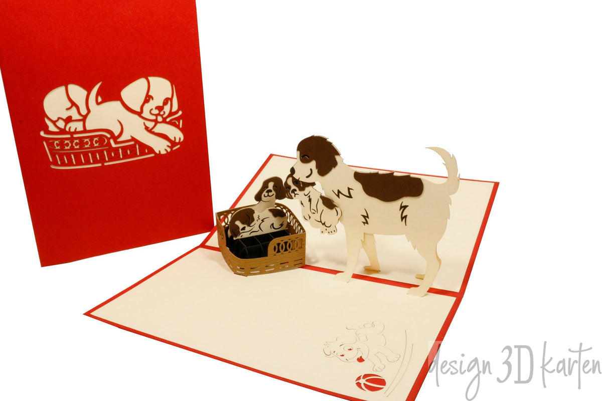 Aufgeklappte Pop-up-Karte mit Hundefamilie, daneben die rote Kartenvorderseite mit Hunde-Scherenschnitt.