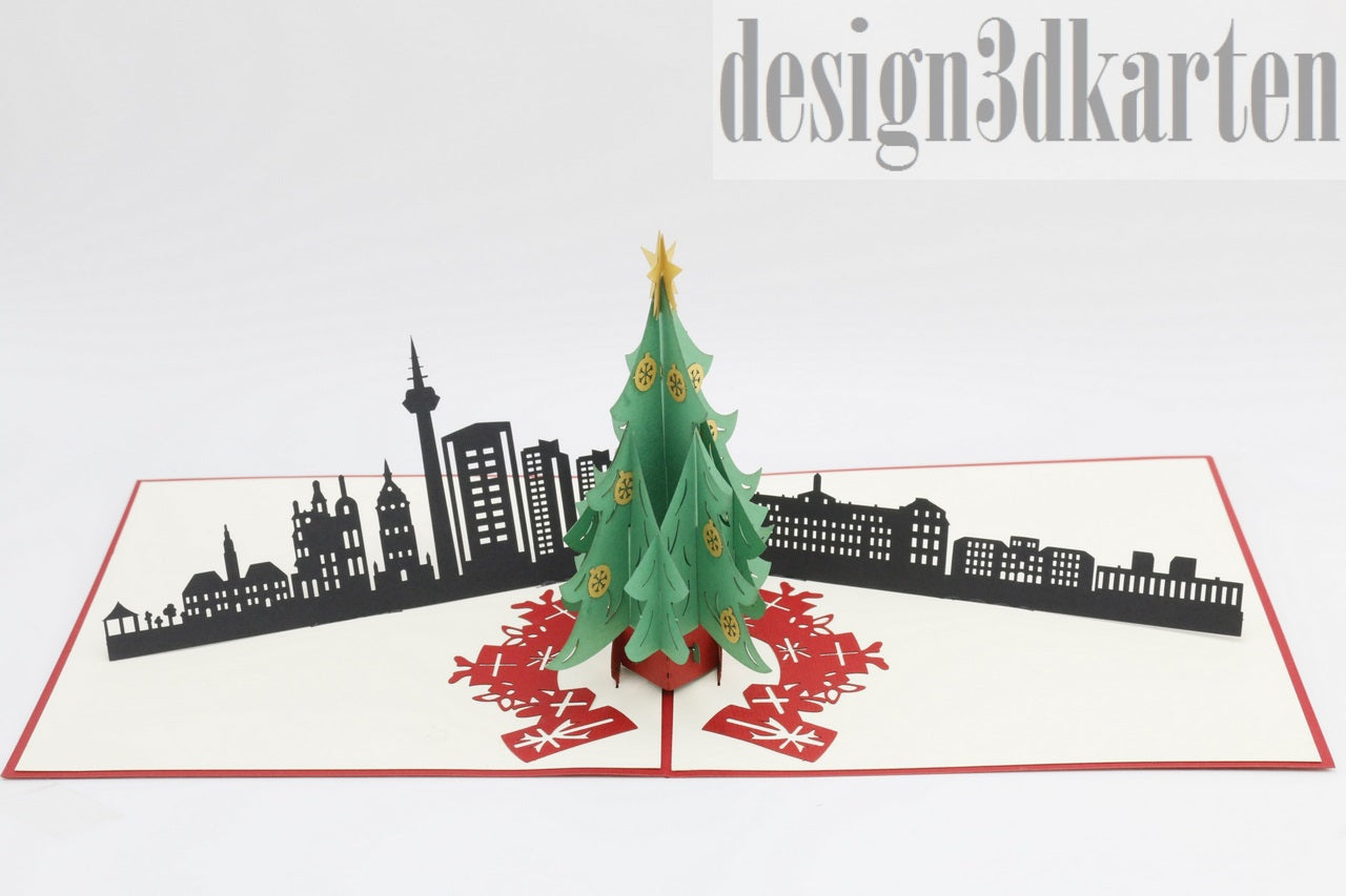Aufgeklappte Pop-up-Karte mit grünem Weihnachtsbaum vor der schwarzen Skyline von Mannheim.