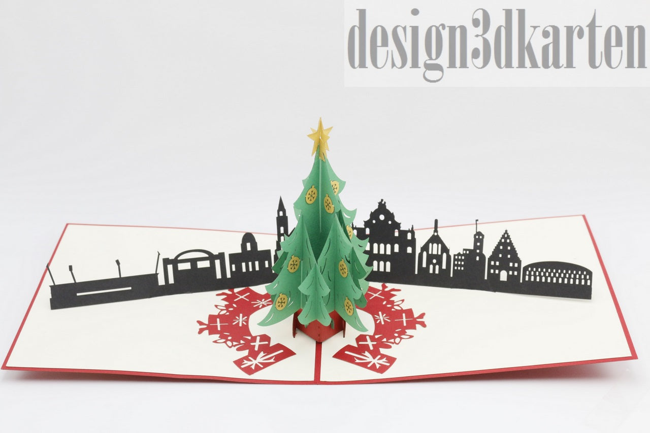Aufgeklappte Pop-up-Karte mit grünem Weihnachtsbaum vor der schwarzen Skyline von Nürnberg.