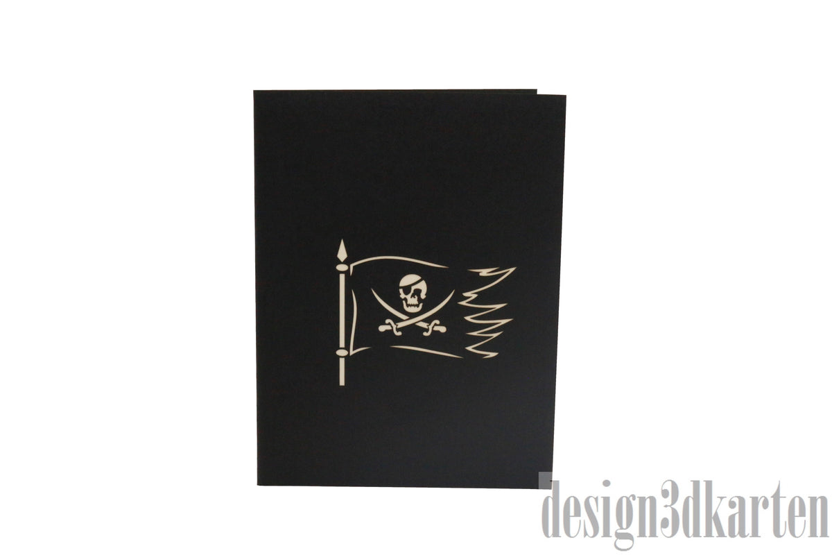 Schwarze Kartenvorderseite mit Piratenflagge, Säbel und Totenkopf als Scherenschnitt.