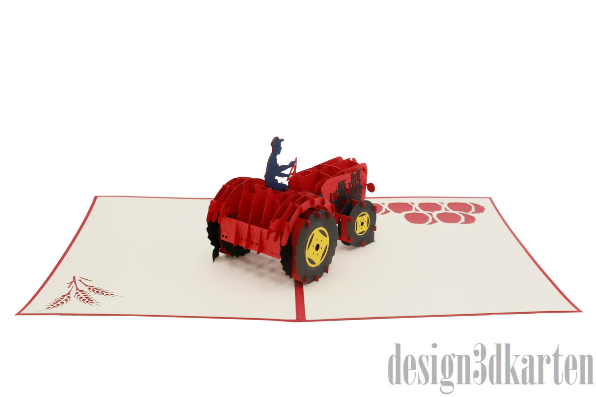 Aufgeklappte Pop-up-Karte mit rotem Oldtimer-Traktor aus Papier, von der anderen Seite fotografiert.