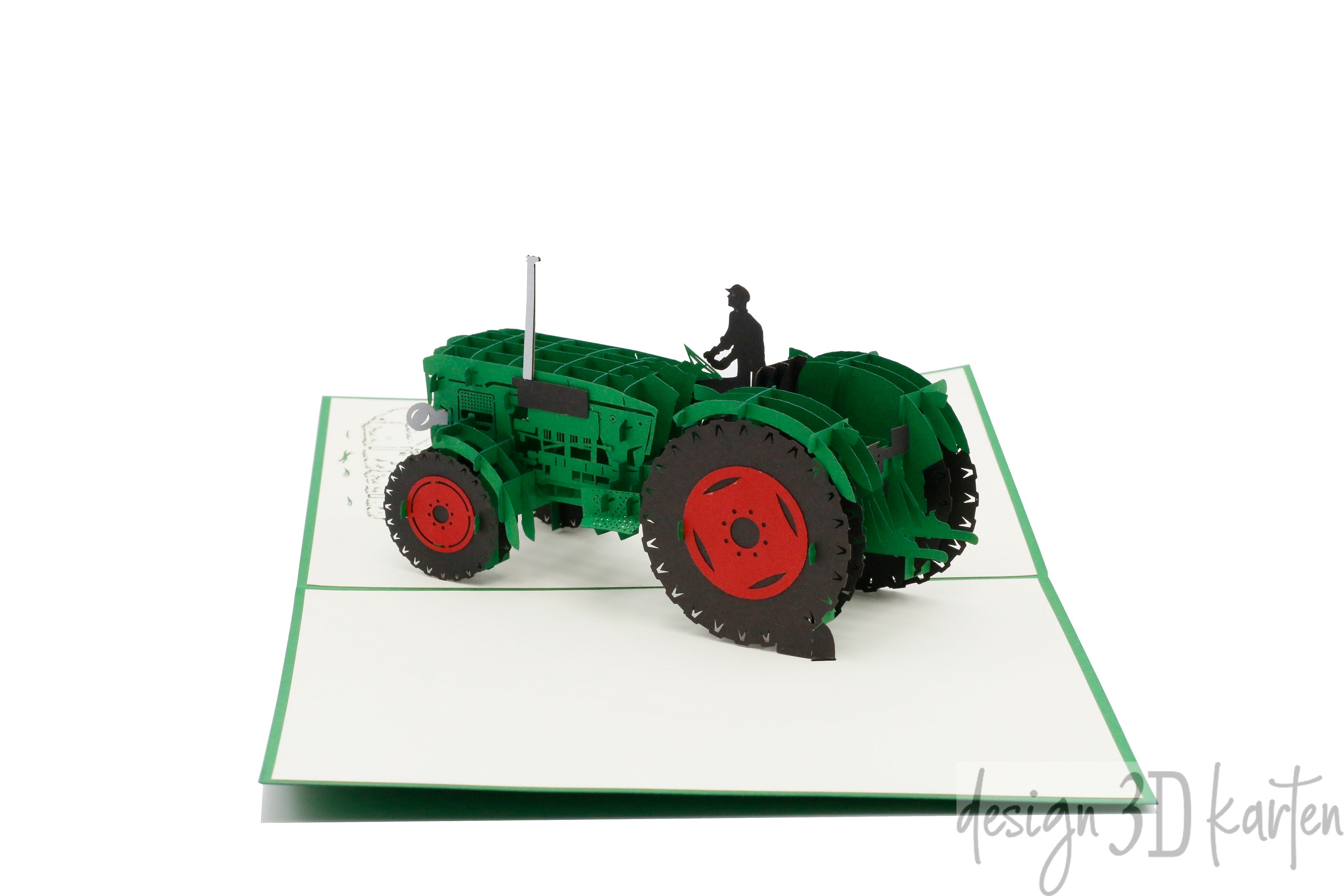 Aufgeklappte Pop-up-Karte mit grünem Oldtimer-Traktor und Fahrerfigur, schräg von oben fotografiert.