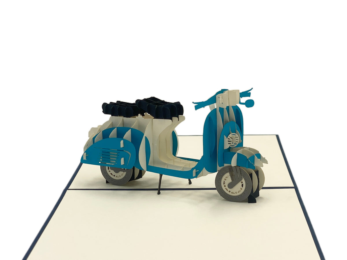 Nahaufnahme der aufgeklappten Pop-up-Karte mit einer blauen Vespa mit Gepäckträger.