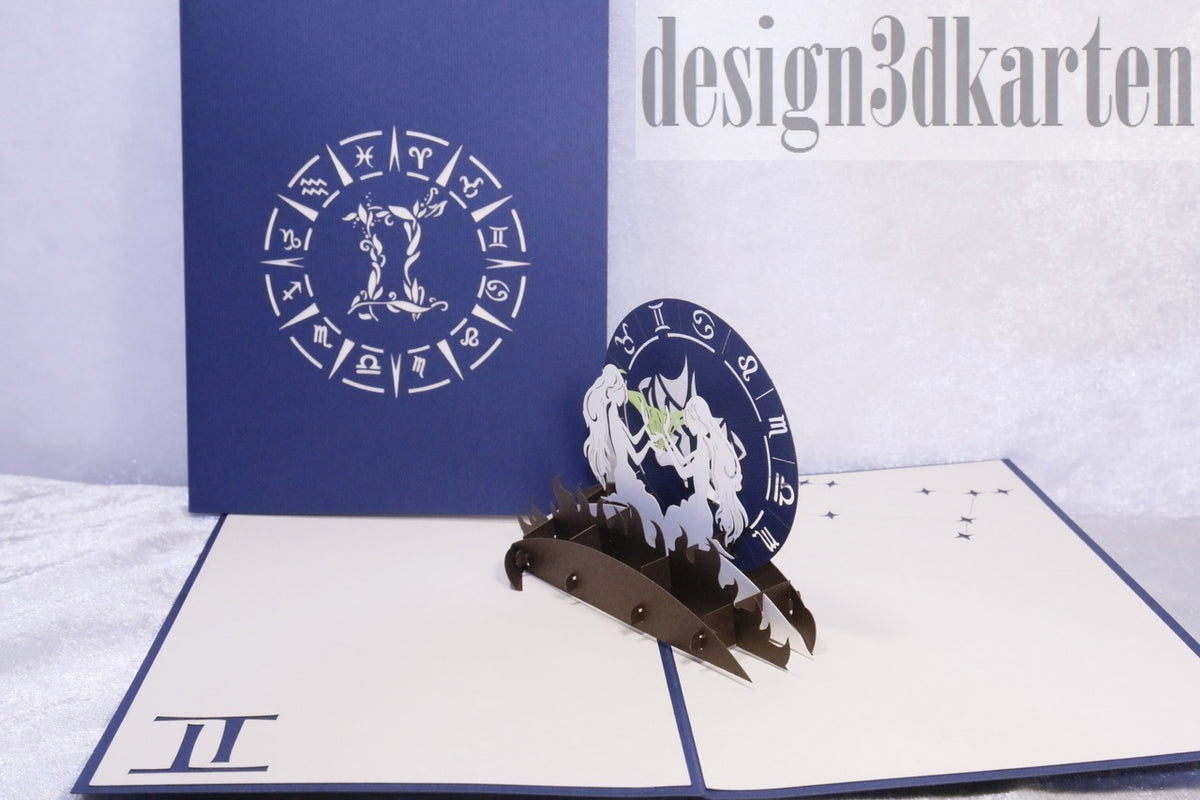 Aufgeklappte Pop-up-Karte mit dem Sternzeichen Zwillinge, daneben die dunkelblaue Kartenvorderseite mit Tierkreisrad.