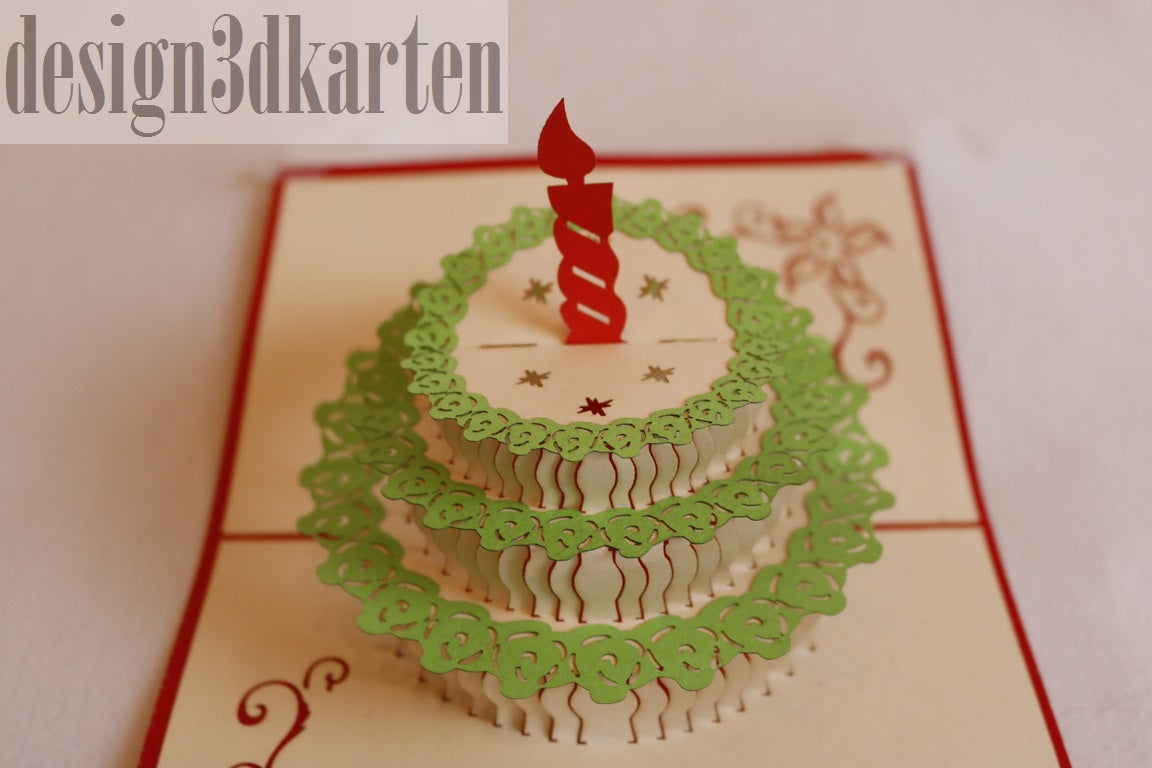 Nahaufnahme der aufgeklappten Pop-up-Karte mit einer Torte mit grünem Spitzendekor und roter Kerze.