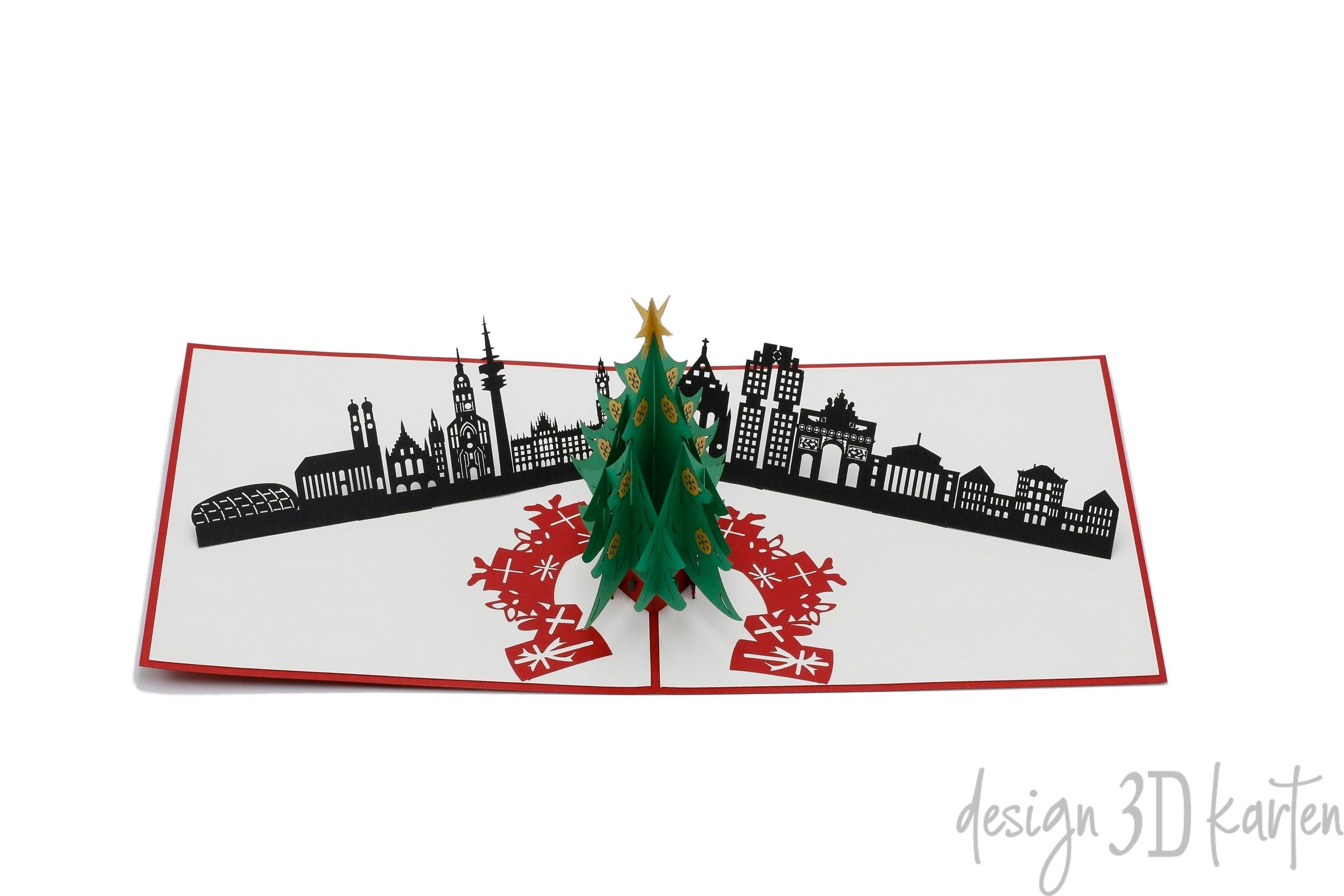 Aufgeklappte Pop-up-Karte mit Weihnachtsbaum vor der schwarzen Skyline von München und roten Geschenken.