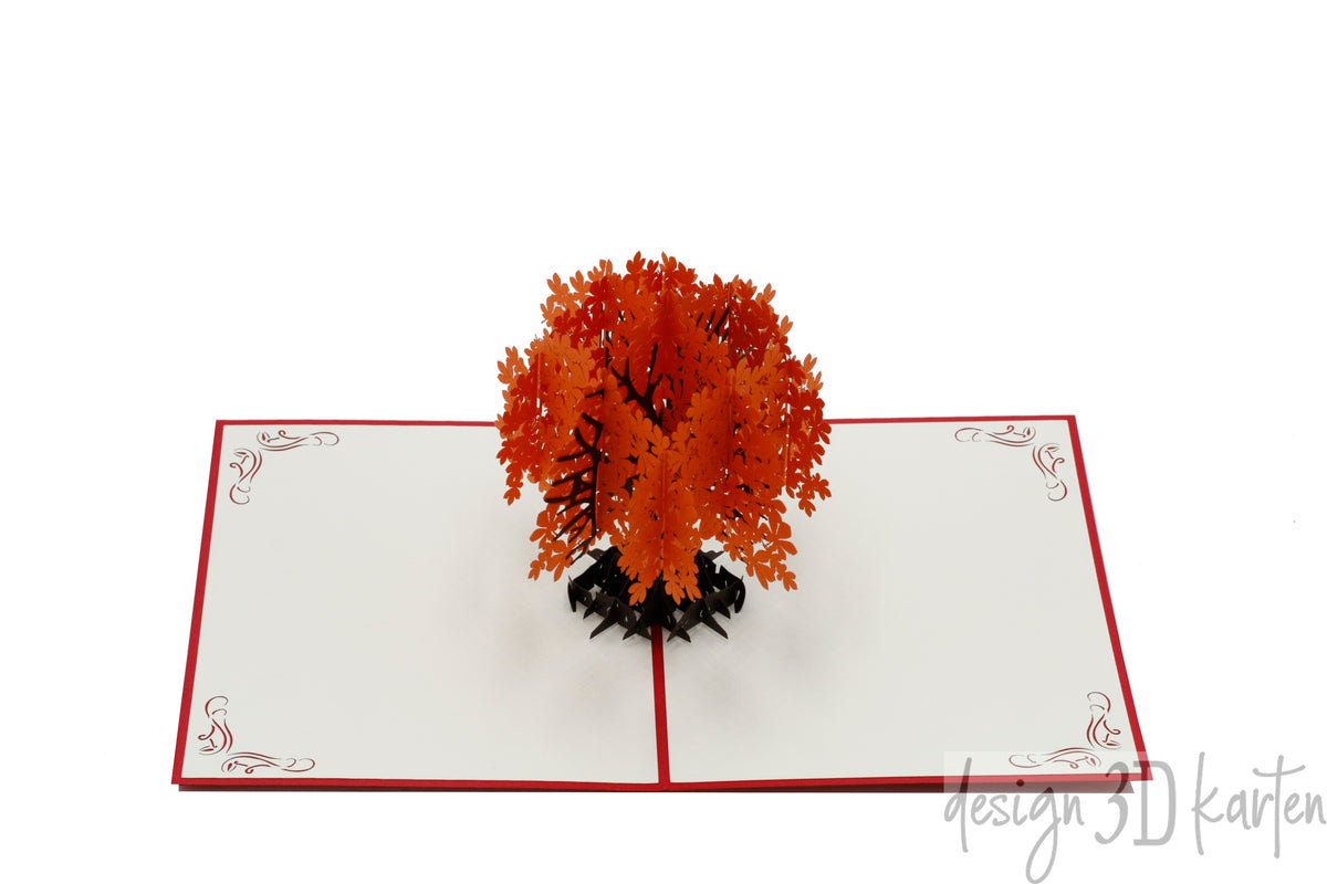 Aufgeklappte Pop-up-Karte mit orangefarbenem Herbstbaum, schräg von der Seite fotografiert.