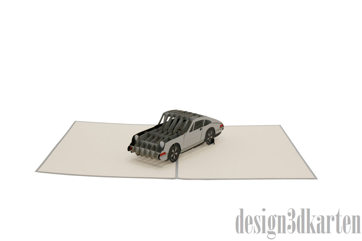 Aufgeklappte Pop-up-Karte mit silbernem Sportwagen, schräg von vorne fotografiert.