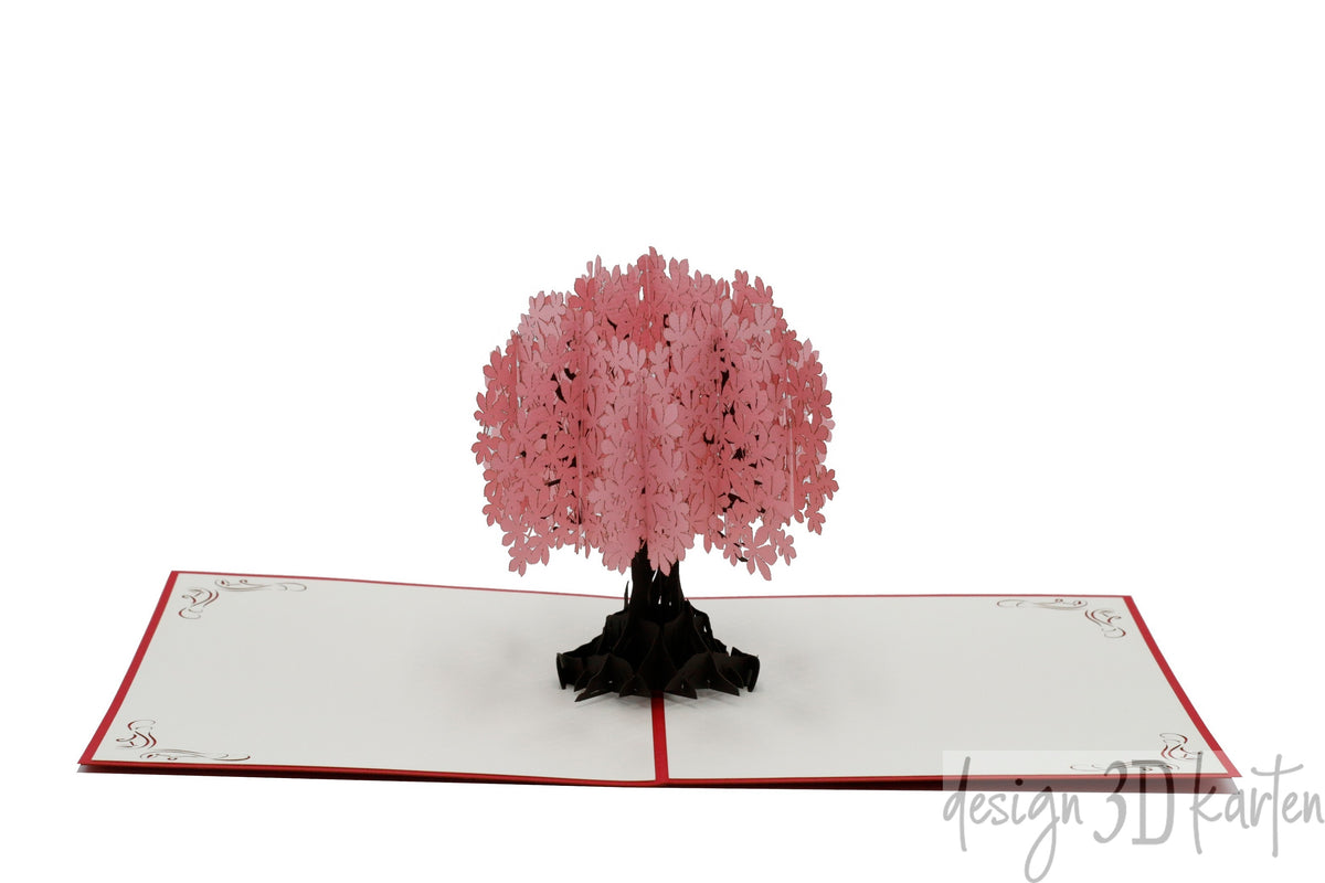 Aufgeklappte Pop-up-Karte mit einem Baum mit rosa Blüten, frontal fotografiert.